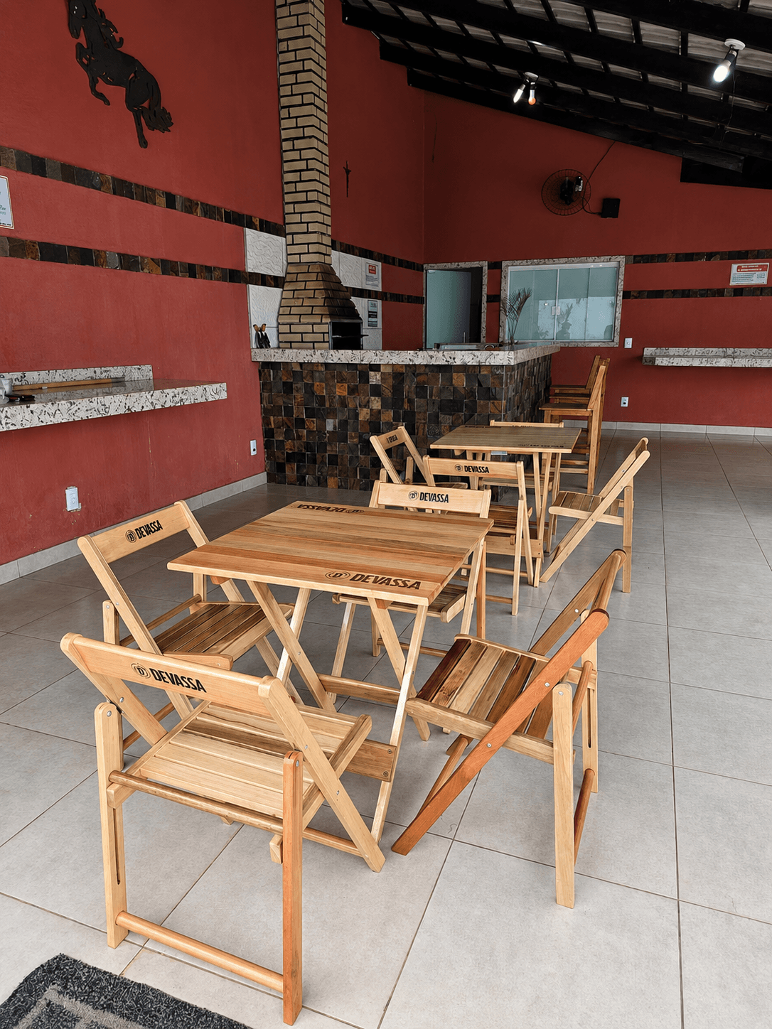 Salão da área gourmet da Vila Agostinis com várias mesas e cadeiras de madeira montadas.