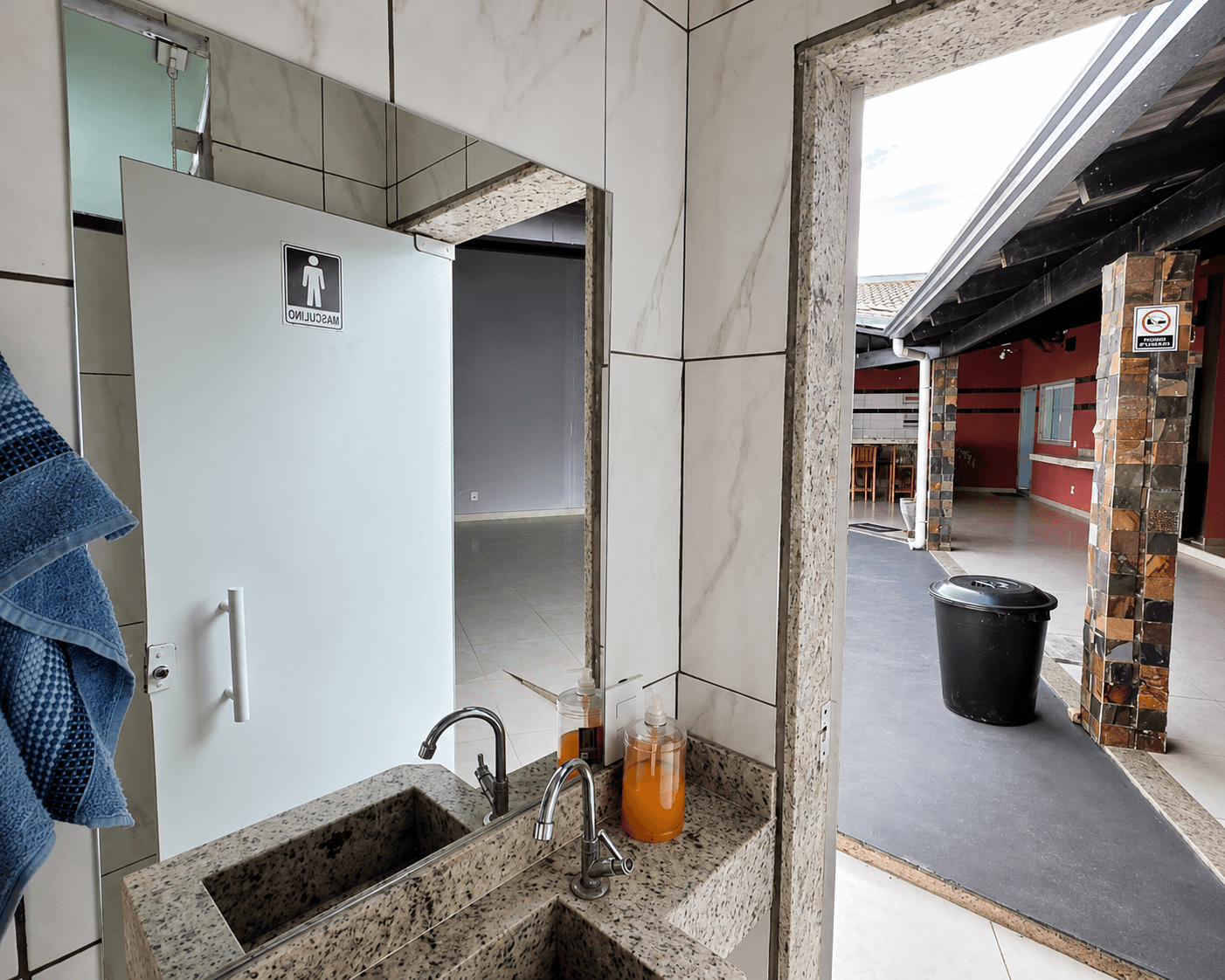 Lavatório do banheiro da Vila Agostinis, com espelho refletindo a porta e o pátio.